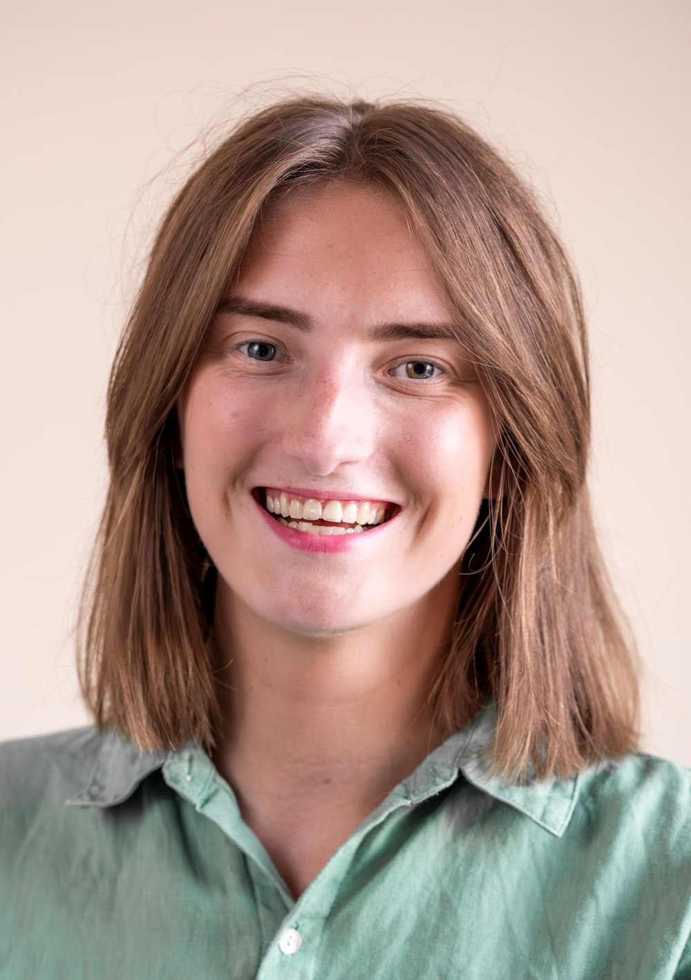 White British woman smiling straight ahead with brown hair. Age ranging between 26 - 30 years old.