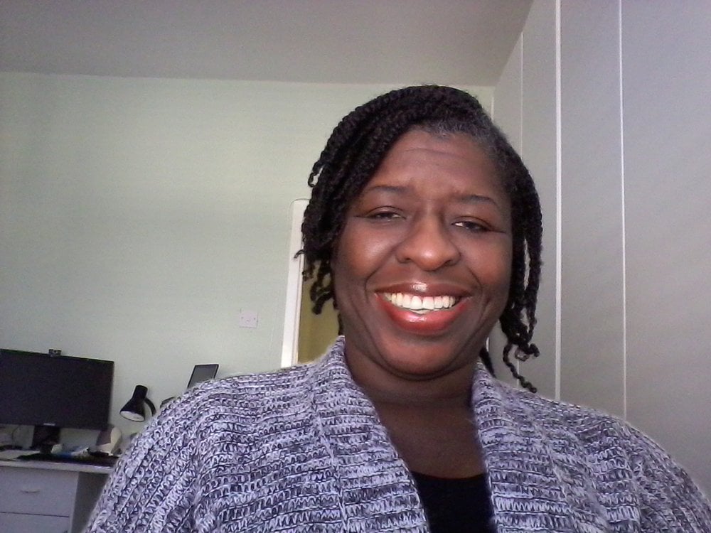 Headshot of Jennifer smiling for the camera. She is a black woman with short black hair. Jennifer is wearing a grey cardigan with a black T-shirt