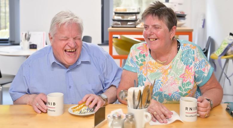 Billy and Sylvia laughing together with cake and tea, at RNIB Scotland's Café VI