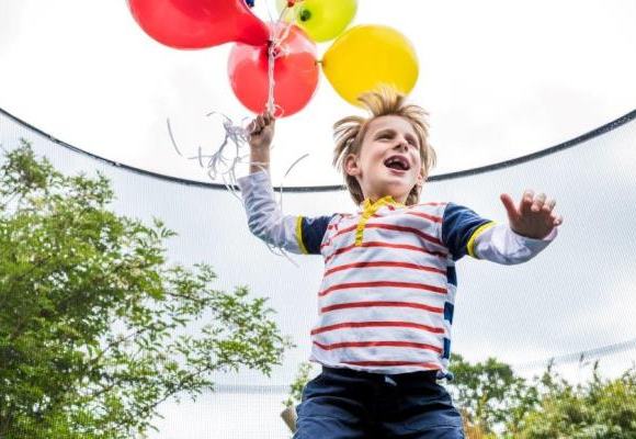 A child running while holding a bunch of balloons.