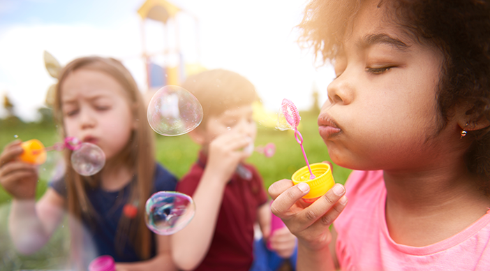 Children blow bubbles together on a sunny day