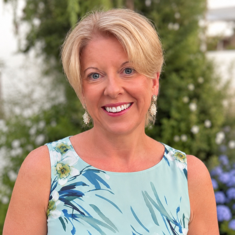 Clare Finney, Chief People Officer at RNIB. Clare has short blonde hair, wears a blue dress, and is standing smiling outside.