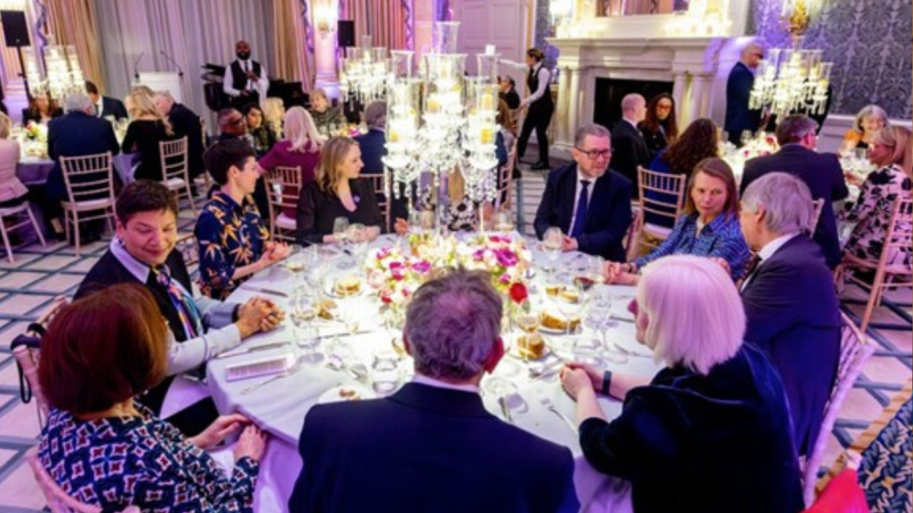 Image description: A group of people sat down at a circular table, at a Claridge's dinner.