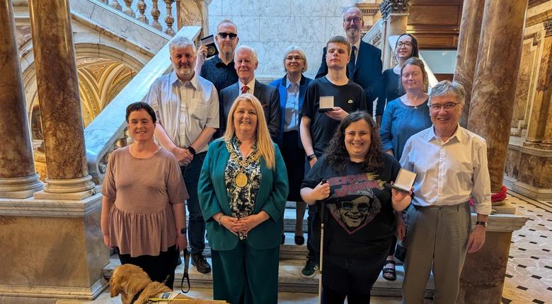 Group photo, participants holding medals. Bottom row left to right: Jen Worral (participant, with guide dog Snowball), Lord Provost, Claire Forde (participant), John McArthur (Glasgow Speakers Club), middle row: James Adams (Director, RNIB Scotland), Cllr Robert Mooney (sponsor), Luke Teasdale (participant), Morag Wilson (participant), Back row: Robert King (participant), Grace Hendry-Nash (Glasgow Speakers Club), Bobby Livingston (Glasgow Speakers Club), and Iona Adamson (RNIB Scotland volunteer).