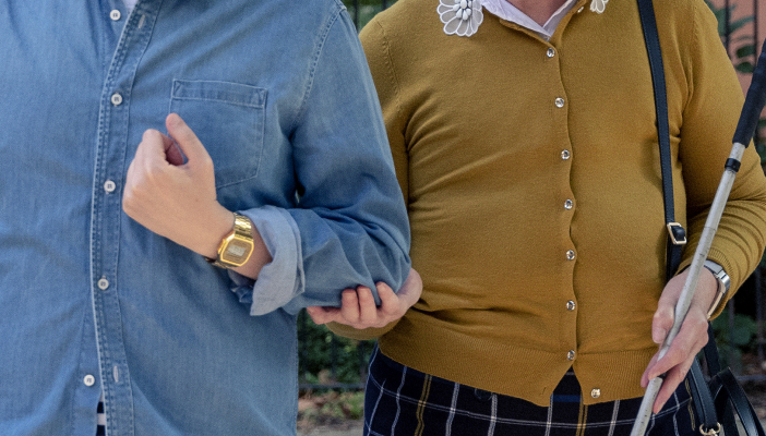 A long cane user holds the elbow of a sighted guide