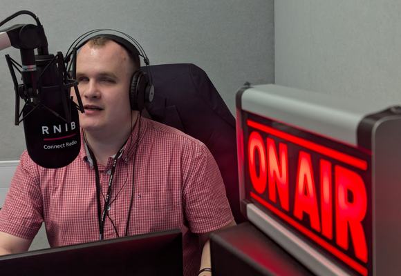 Hubert sat next to a red 'on air' sign, talking into a large radio microphone.