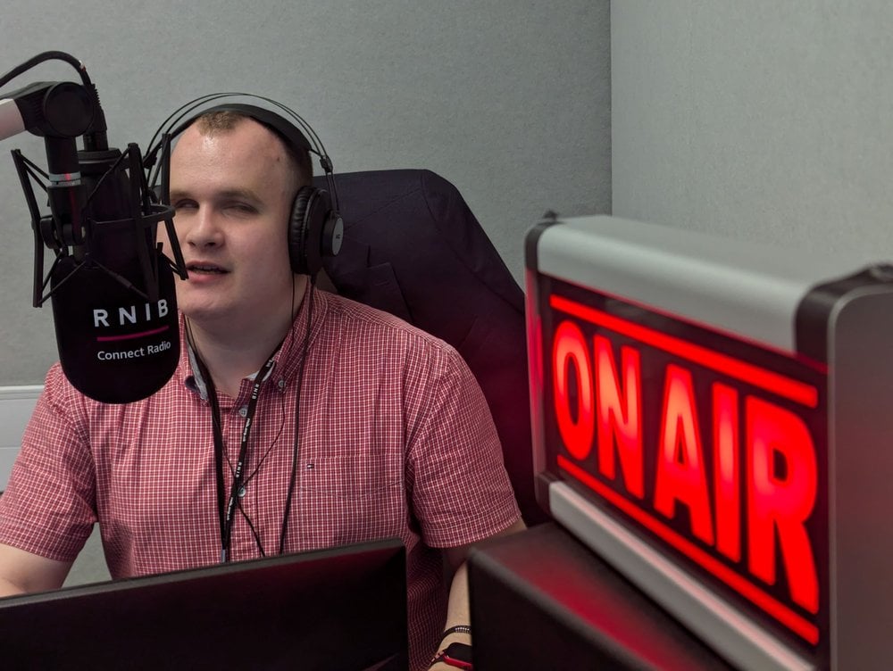 Hubert sat next to a red 'on air' sign, talking into a large radio microphone.