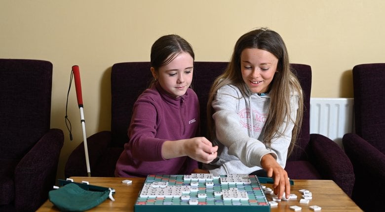 Image shows two people playing large-print scrabble