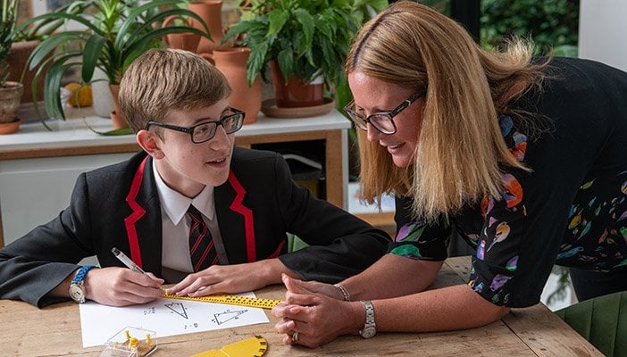 A pupil working with a teacher on a maths lesson.