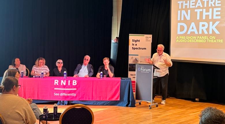Country Director RNIB Northern Ireland Robert Shilliday stands compering panel consisting of: (L-R) Lisa Heaney(Box Office and Access Manager, Millennium Forum); Jacqueline McFarland (Audio describer); lived experience speakers Annemarie Houston and Richard Moore; Jonny Marshall(RNIB Media, Culture and Immersive Technologies team). Screen in background features 'Theatre in the Dark' title screen with image of person wearing headset in theatre