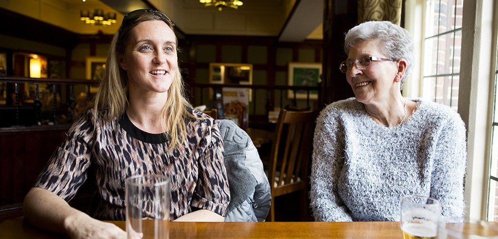 Two ladies sitting at a table in a pub enjoying a conversation.
