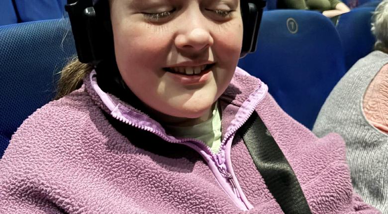 Eryn wearing audio description headset in cinema and smiling to camera