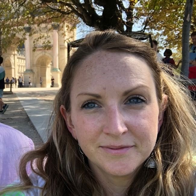 Nina Walker, a white middle aged woman with brown hair smiling in front of an ornate building